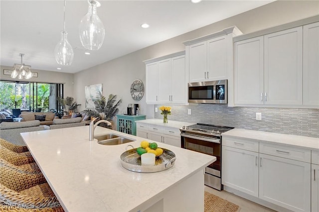 kitchen with appliances with stainless steel finishes, a sink, a center island with sink, and tasteful backsplash