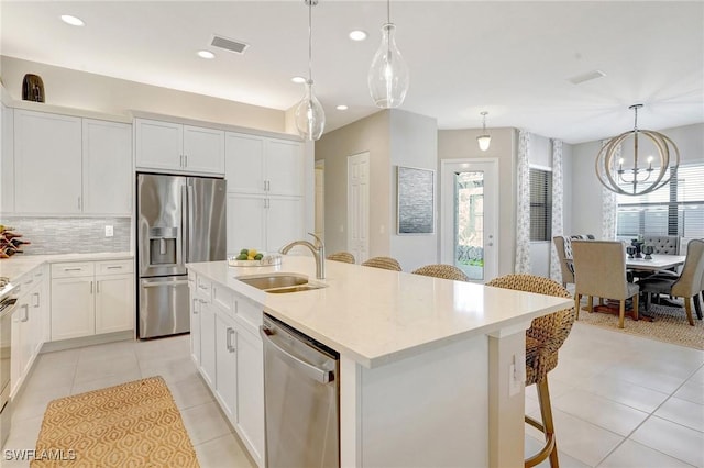 kitchen with light tile patterned floors, stainless steel appliances, tasteful backsplash, visible vents, and a sink