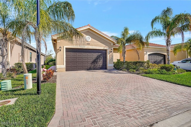 mediterranean / spanish home featuring decorative driveway, an attached garage, and stucco siding