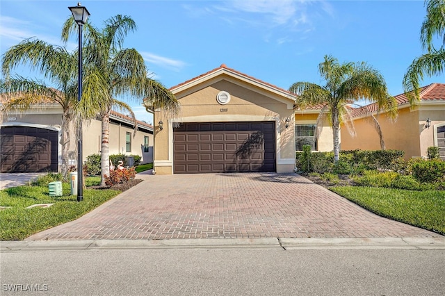 view of front of property with decorative driveway, an attached garage, and stucco siding