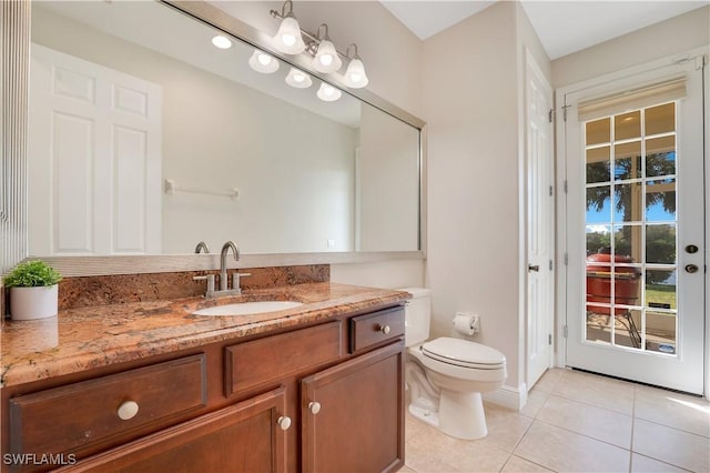 bathroom with toilet, plenty of natural light, tile patterned flooring, and vanity