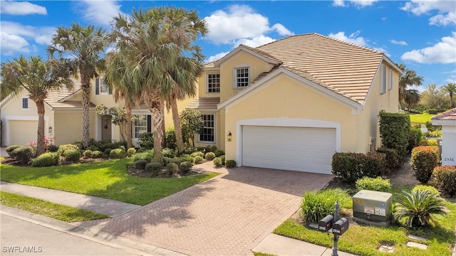 view of front facade with decorative driveway, a tile roof, stucco siding, an attached garage, and a front yard