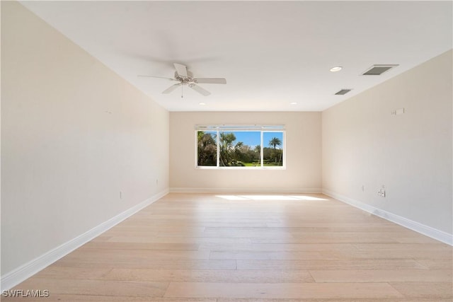 spare room featuring light wood finished floors, visible vents, and baseboards