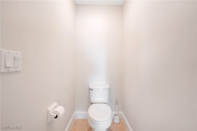 bathroom with toilet, baseboards, and tile patterned floors