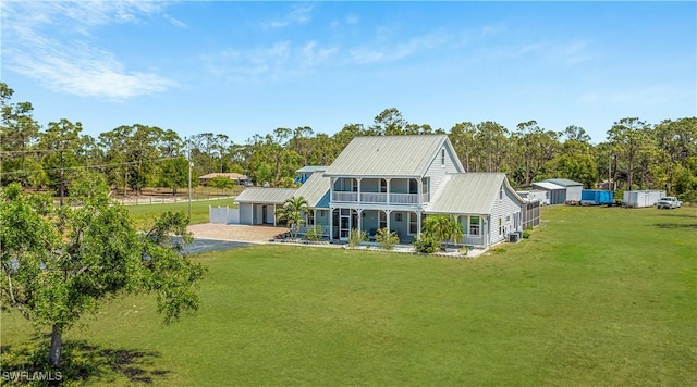 rear view of property with a yard, a porch, metal roof, and a balcony