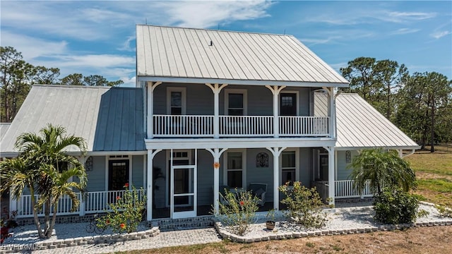 view of front facade with metal roof, a balcony, covered porch, and a standing seam roof