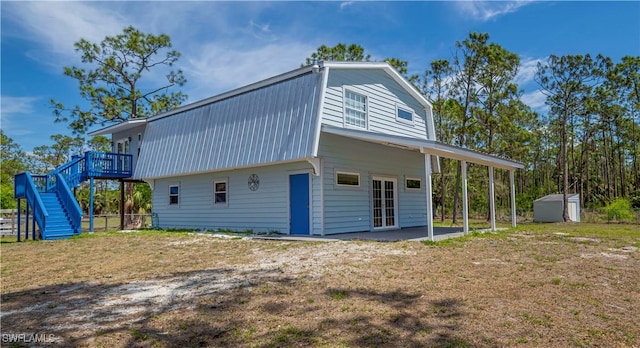 19150 Gottarde Rd, North Fort Myers, FL 33917 - view of home's exterior featuring a gambrel roof, stairway, metal roof, a wooden deck, and a patio area
