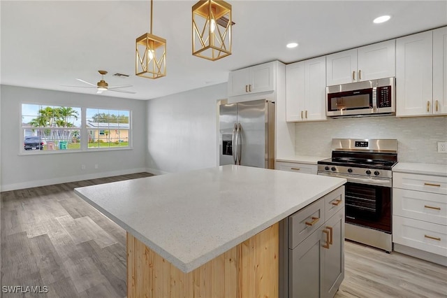 kitchen with a center island, stainless steel appliances, visible vents, decorative backsplash, and light wood-style floors