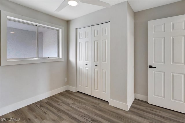 unfurnished bedroom with a closet, ceiling fan, baseboards, and wood finished floors