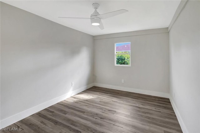 empty room with dark wood-type flooring, baseboards, and a ceiling fan