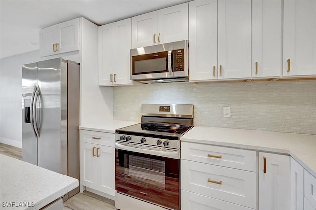 kitchen with stainless steel appliances, tasteful backsplash, light countertops, white cabinetry, and light wood-type flooring