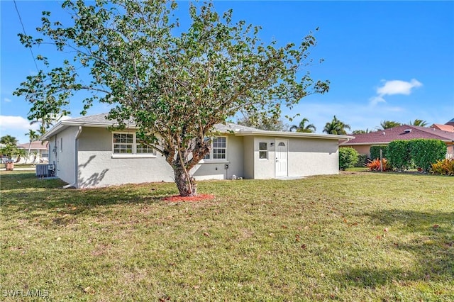 back of property with stucco siding, cooling unit, and a yard