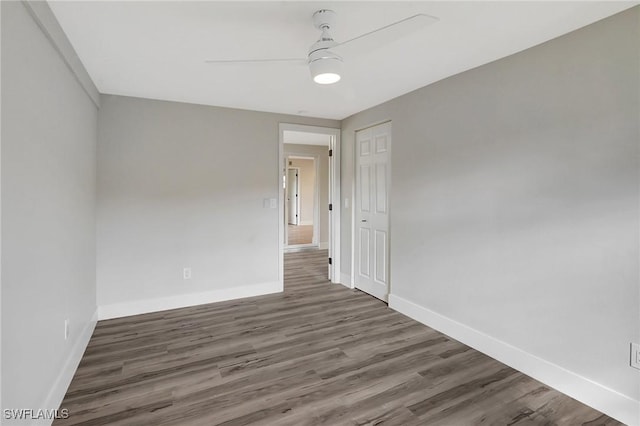 unfurnished room featuring dark wood-style floors, baseboards, and a ceiling fan