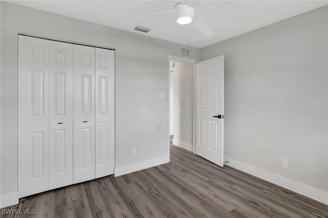 unfurnished bedroom with a closet, visible vents, ceiling fan, wood finished floors, and baseboards