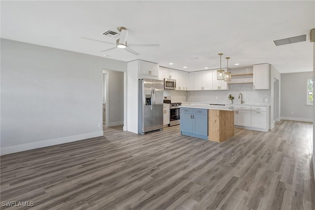 kitchen featuring appliances with stainless steel finishes, a center island, white cabinets, and light countertops