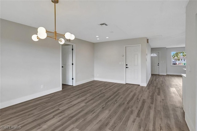 spare room with dark wood-style floors, visible vents, and baseboards