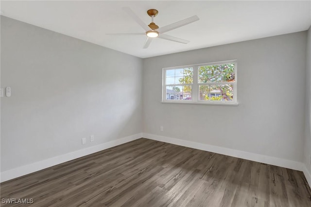 spare room featuring ceiling fan, baseboards, and dark wood-type flooring