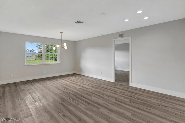 unfurnished room featuring dark wood-style floors, an inviting chandelier, visible vents, and baseboards