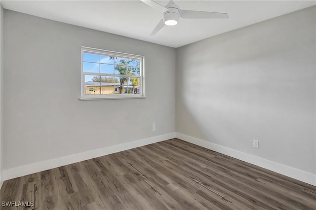 empty room with a ceiling fan, dark wood finished floors, and baseboards