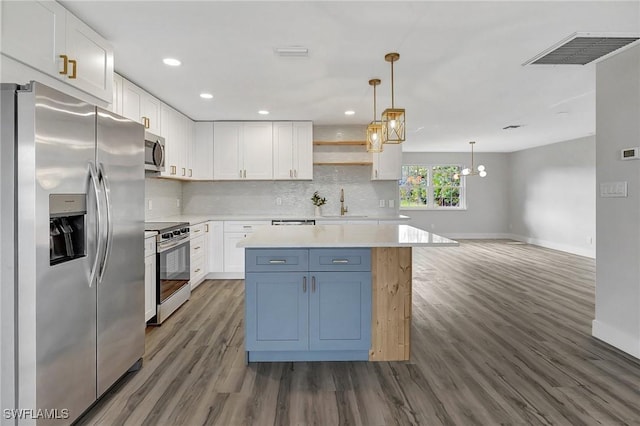 kitchen featuring stainless steel appliances, white cabinets, light countertops, and decorative light fixtures