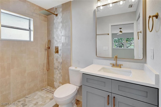 bathroom with toilet, a tile shower, and vanity