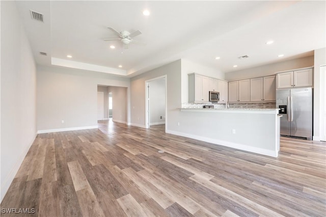 kitchen featuring visible vents, decorative backsplash, appliances with stainless steel finishes, open floor plan, and light stone countertops