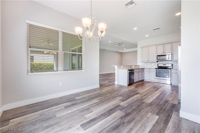 kitchen featuring stainless steel appliances, visible vents, hanging light fixtures, open floor plan, and a peninsula