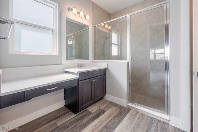 bathroom featuring a shower stall, baseboards, wood finished floors, and vanity