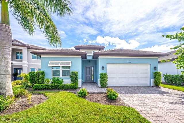 view of front of property featuring an attached garage, decorative driveway, and stucco siding