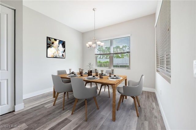 dining area with light wood-style floors, baseboards, and an inviting chandelier