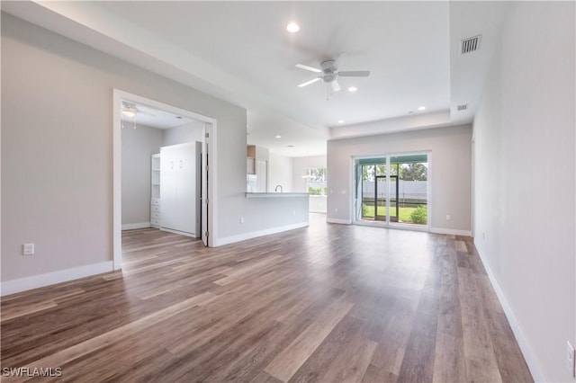 unfurnished living room with visible vents, light wood-type flooring, a ceiling fan, and baseboards