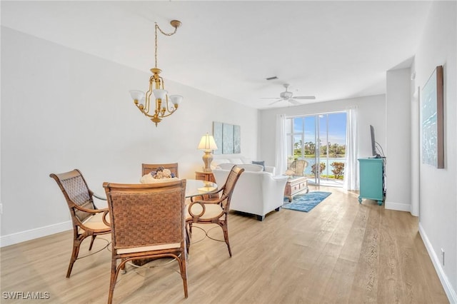 dining space featuring baseboards, visible vents, light wood finished floors, and ceiling fan with notable chandelier