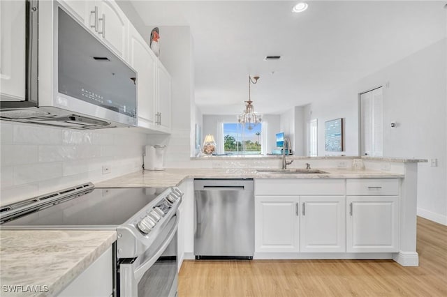 kitchen with appliances with stainless steel finishes, white cabinetry, a sink, and hanging light fixtures