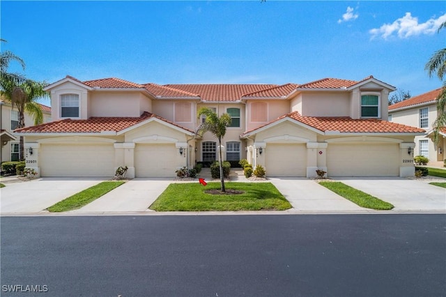 mediterranean / spanish home with a garage, concrete driveway, a tiled roof, and stucco siding