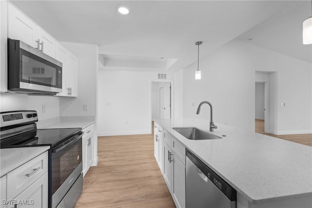 kitchen with an island with sink, decorative light fixtures, stainless steel appliances, white cabinetry, and a sink