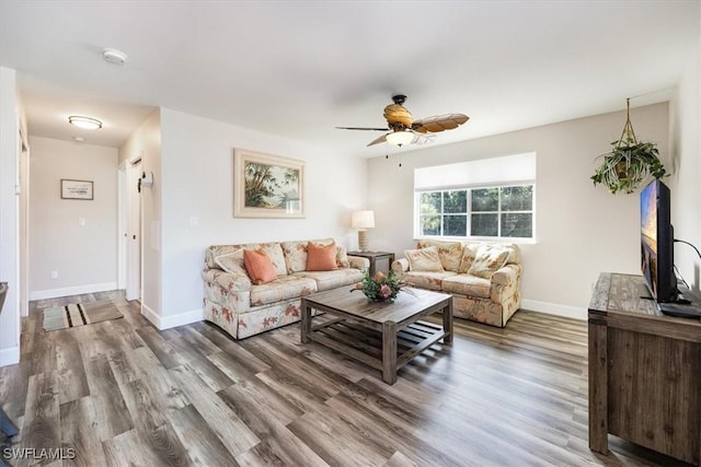 living area featuring wood finished floors, a ceiling fan, and baseboards