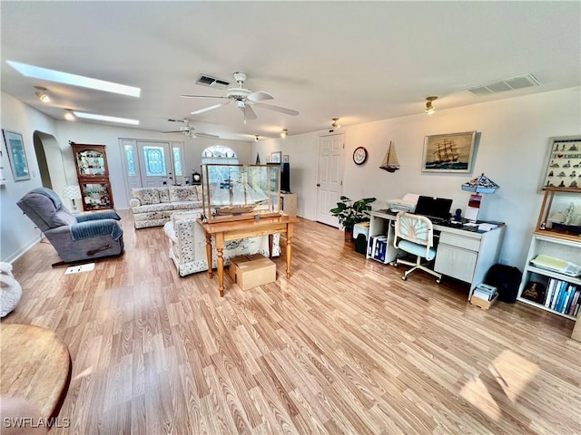 living room with arched walkways, visible vents, and light wood-style floors