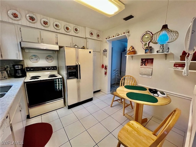 kitchen with light tile patterned floors, under cabinet range hood, white appliances, light countertops, and decorative light fixtures