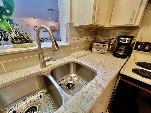 interior space with range with electric stovetop, visible vents, backsplash, light brown cabinets, and a sink