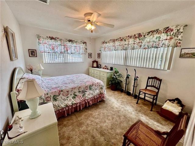 carpeted bedroom featuring ceiling fan and a textured ceiling