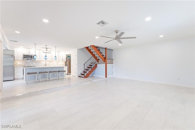 unfurnished living room featuring ceiling fan, recessed lighting, visible vents, baseboards, and stairway