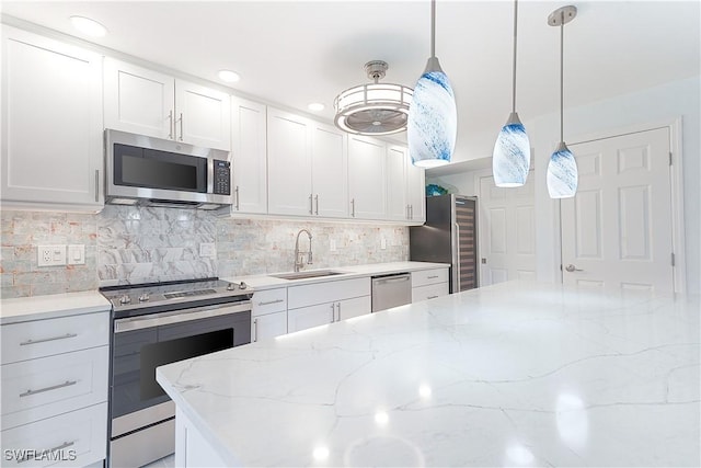 kitchen featuring white cabinets, appliances with stainless steel finishes, backsplash, and a sink