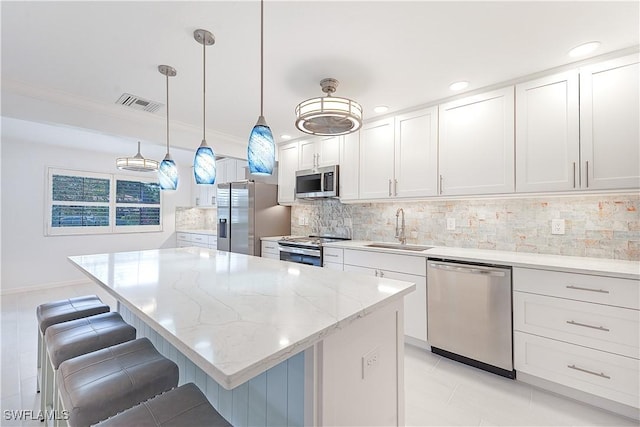 kitchen with a breakfast bar area, stainless steel appliances, visible vents, white cabinetry, and a sink