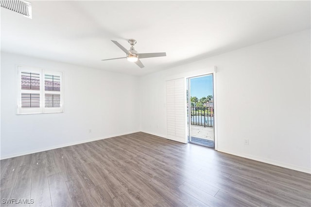 empty room with baseboards, ceiling fan, visible vents, and wood finished floors