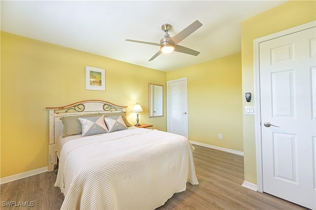 bedroom with a ceiling fan, baseboards, and wood finished floors