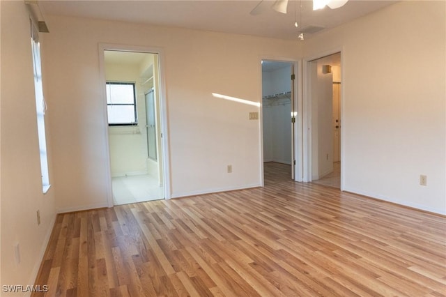 spare room featuring ceiling fan, light wood-style flooring, and baseboards