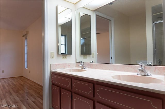 full bathroom with double vanity, baseboards, a sink, and wood finished floors