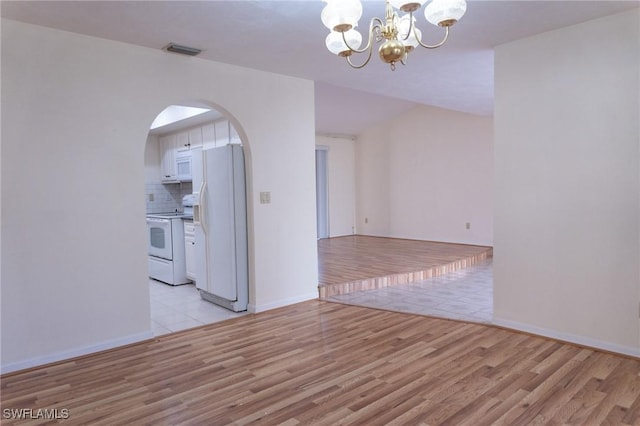 unfurnished room featuring arched walkways, a chandelier, visible vents, baseboards, and light wood-type flooring