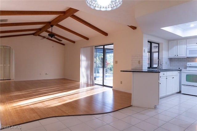 kitchen with light tile patterned floors, white appliances, open floor plan, and a sink