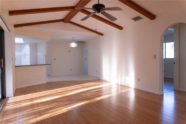 unfurnished living room with light wood-style floors, arched walkways, visible vents, and vaulted ceiling with beams